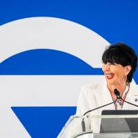 President Mantella smiling of to the side as she stands at podium giving speech